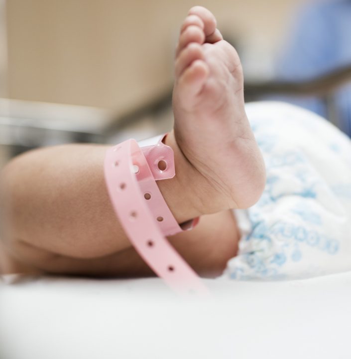 newborn baby feet with hospital id band around ankle